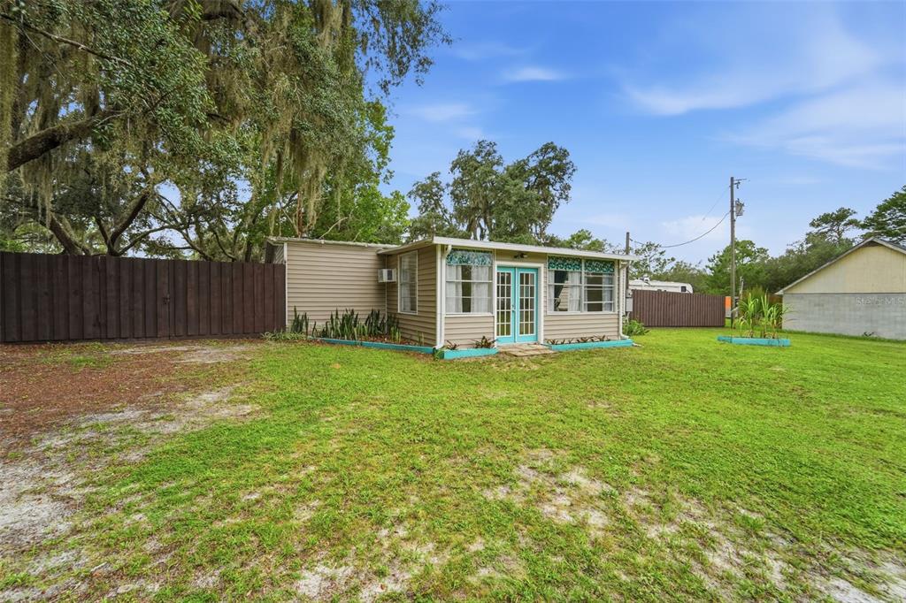 A small, light-colored house with a flat roof and blue double doors sits on grass — 31622 ANOTHER ANNA ROAD, DELAND, FL