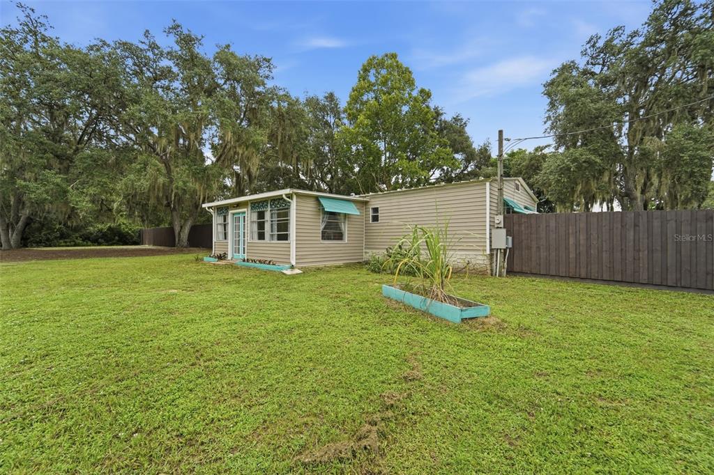 A single-story house with beige siding, a turquoise door, and a wooden privacy fence — 31622 ANOTHER ANNA ROAD, DELAND, FL