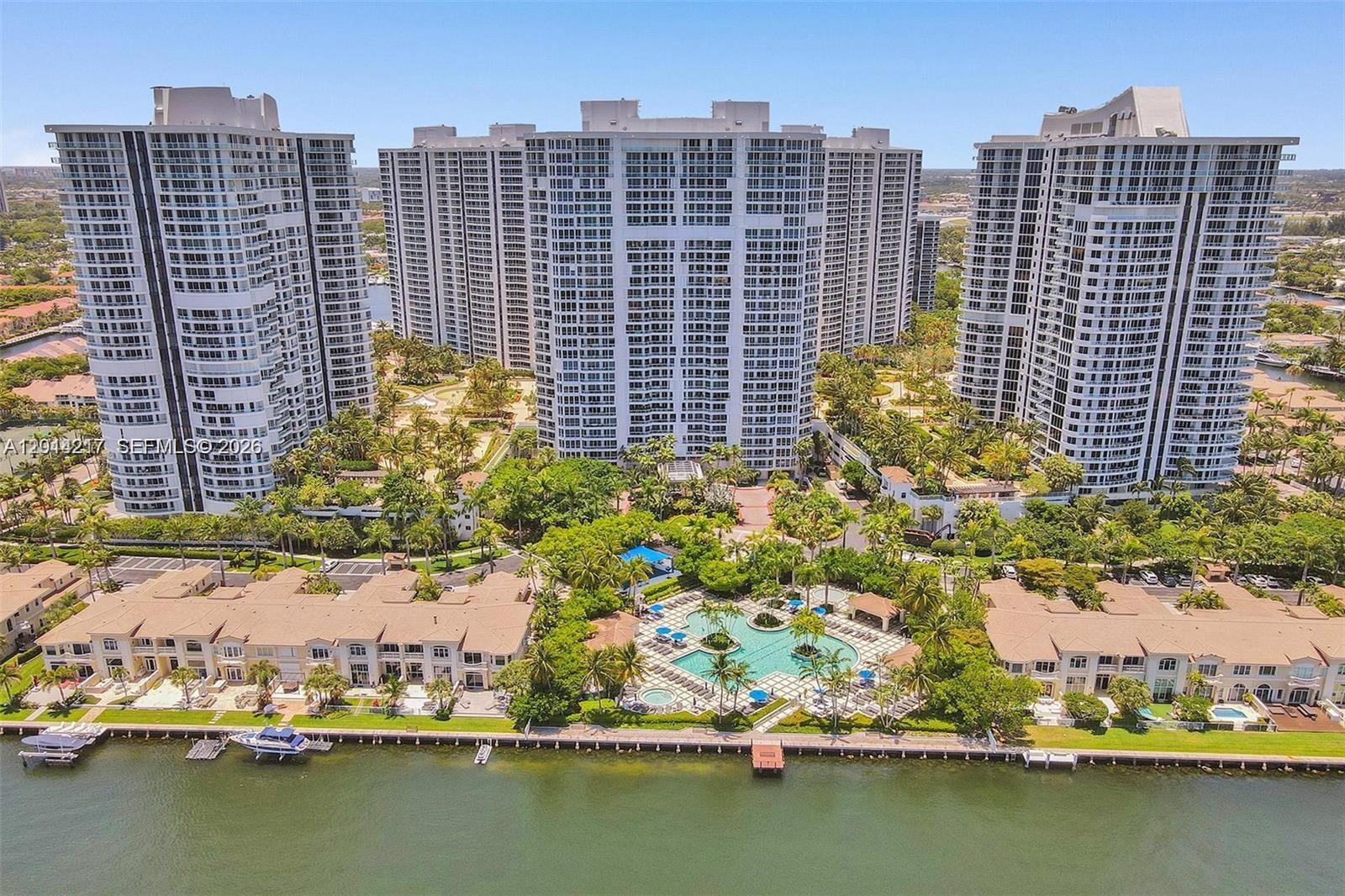 An aerial view of three high-rise residential towers overlooking a pool and a waterfront — 21050 Point Pl # 302, Aventura FL 33180, AVENTURA, FL