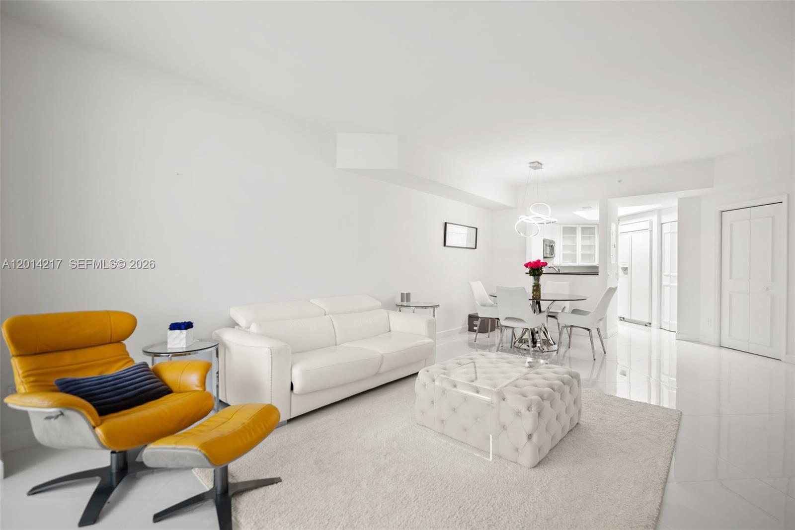 A bright living and dining area features white tile floors, a white sofa, and yellow chair — 21050 Point Pl # 302, Aventura FL 33180, AVENTURA, FL