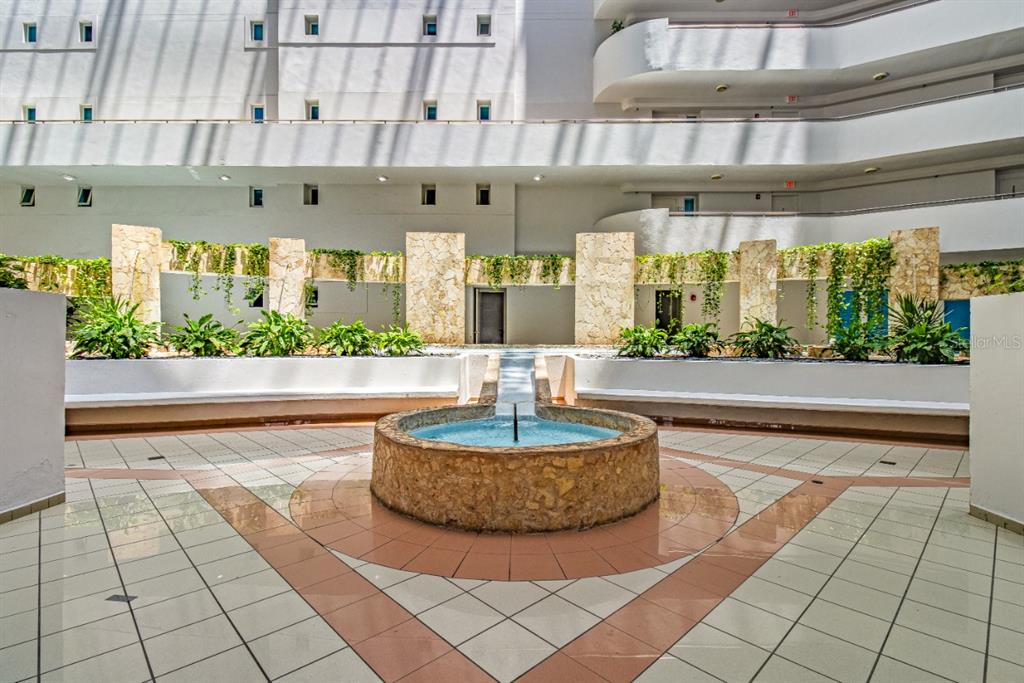 A circular stone fountain sits in the center of a tiled courtyard with tiered balconies — 550 AVENIDA CONSTITUCION UNIT 810, SAN JUAN, PR