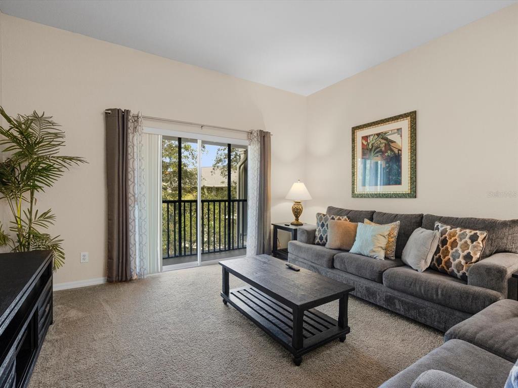 A living room features a gray sofa, a coffee table, and a sliding glass door — 713 LUCAYA LOOP UNIT 1301, DAVENPORT, FL