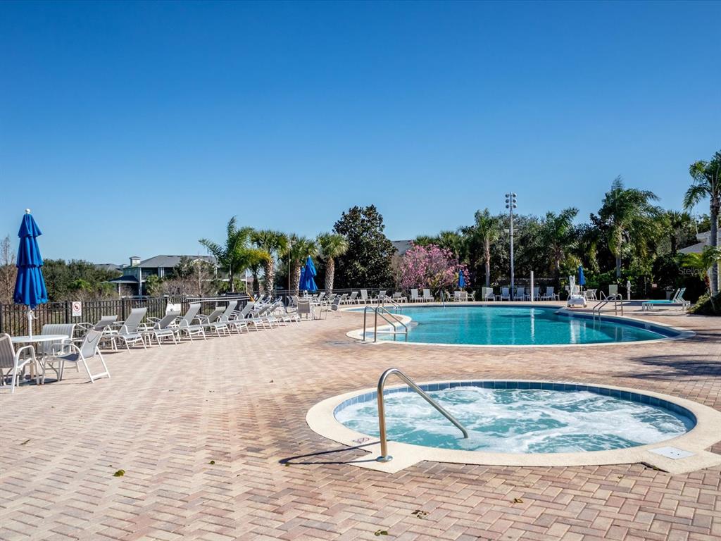 A swimming pool and hot tub are surrounded by lounge chairs on a brick patio — 713 LUCAYA LOOP UNIT 1301, DAVENPORT, FL