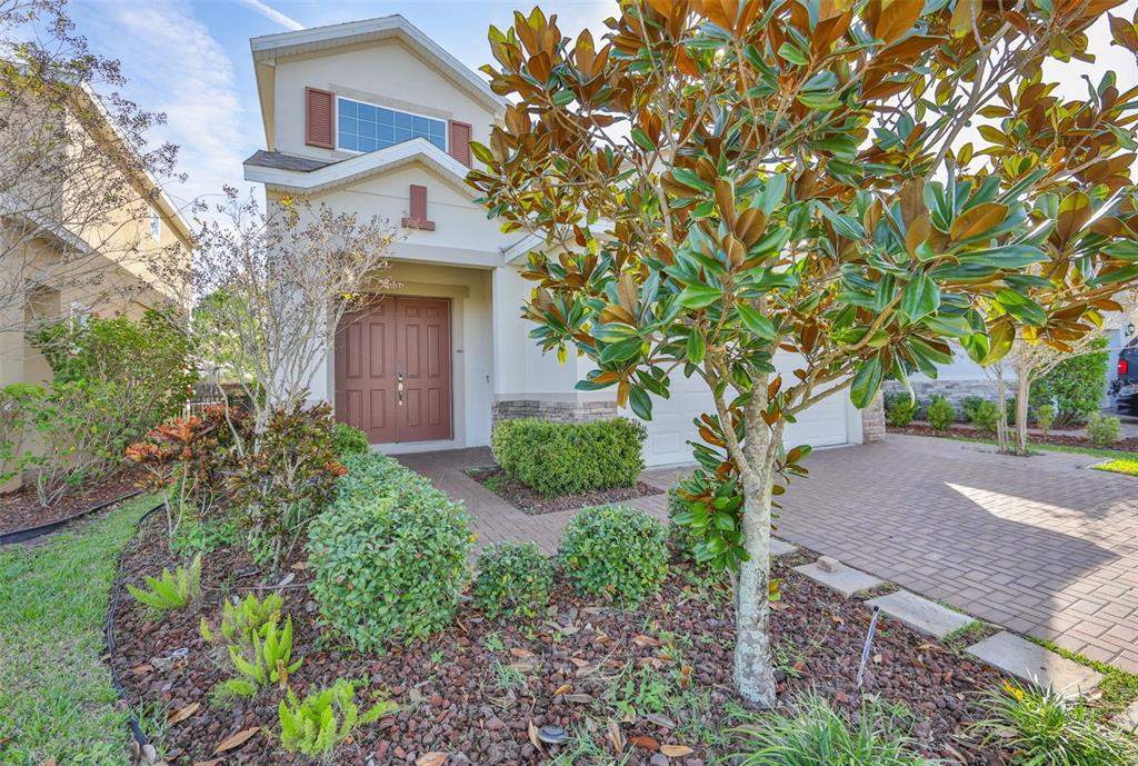 A two-story house with a brick driveway, a front garden, and a brown double door — 6207 VOYAGERS PLACE, APOLLO BEACH, FL