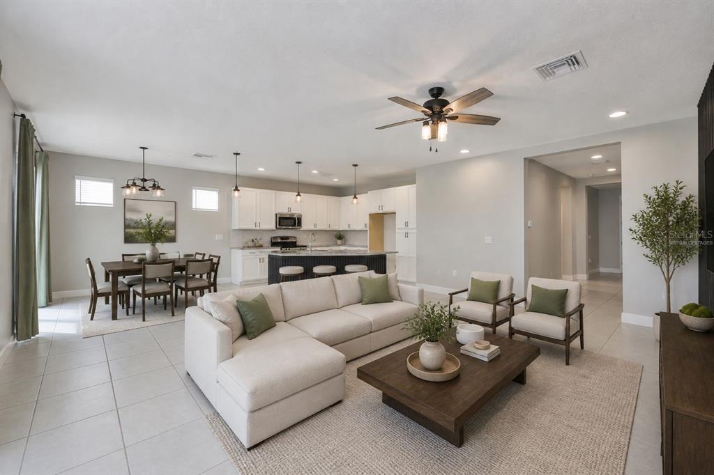 An open-concept living room and kitchen featuring a sectional sofa, dining area, and island — 6207 VOYAGERS PLACE, APOLLO BEACH, FL