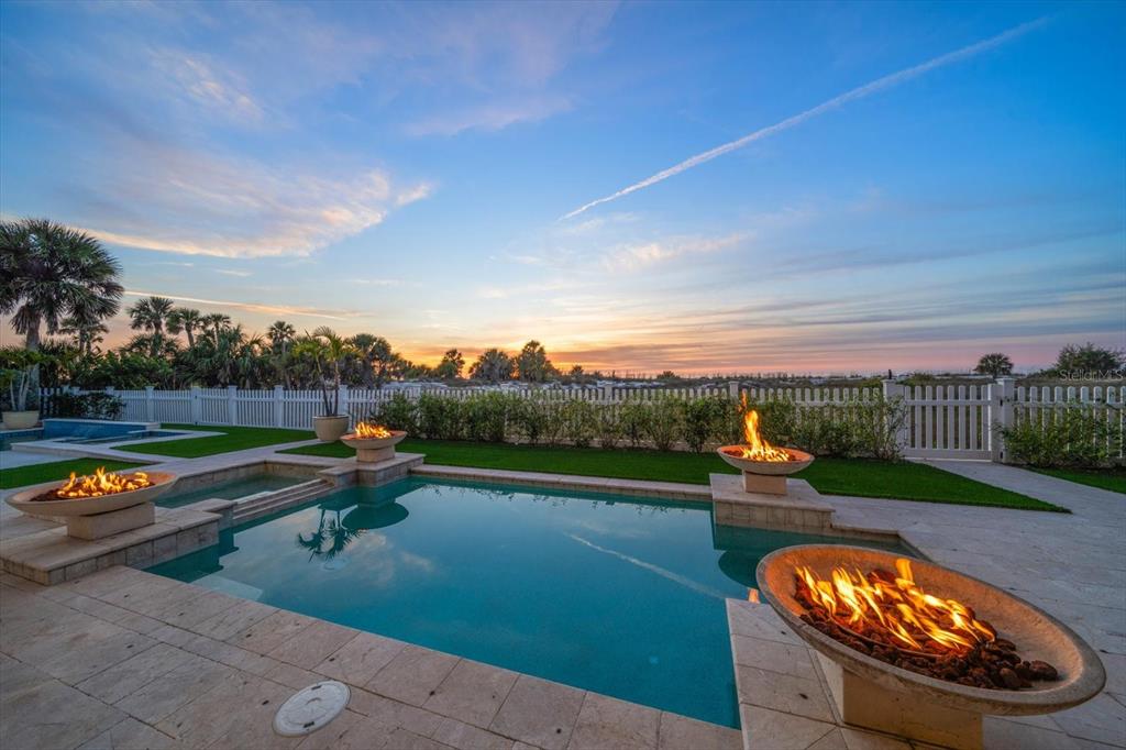 A swimming pool with three fire bowls sits on a patio at sunset — 1040 ELDORADO AVENUE, CLEARWATER BEACH, FL