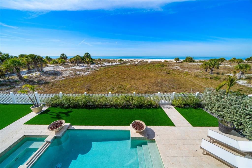 An elevated view of a swimming pool, patio, and lawn overlooking a beach and ocean — 1040 ELDORADO AVENUE, CLEARWATER BEACH, FL