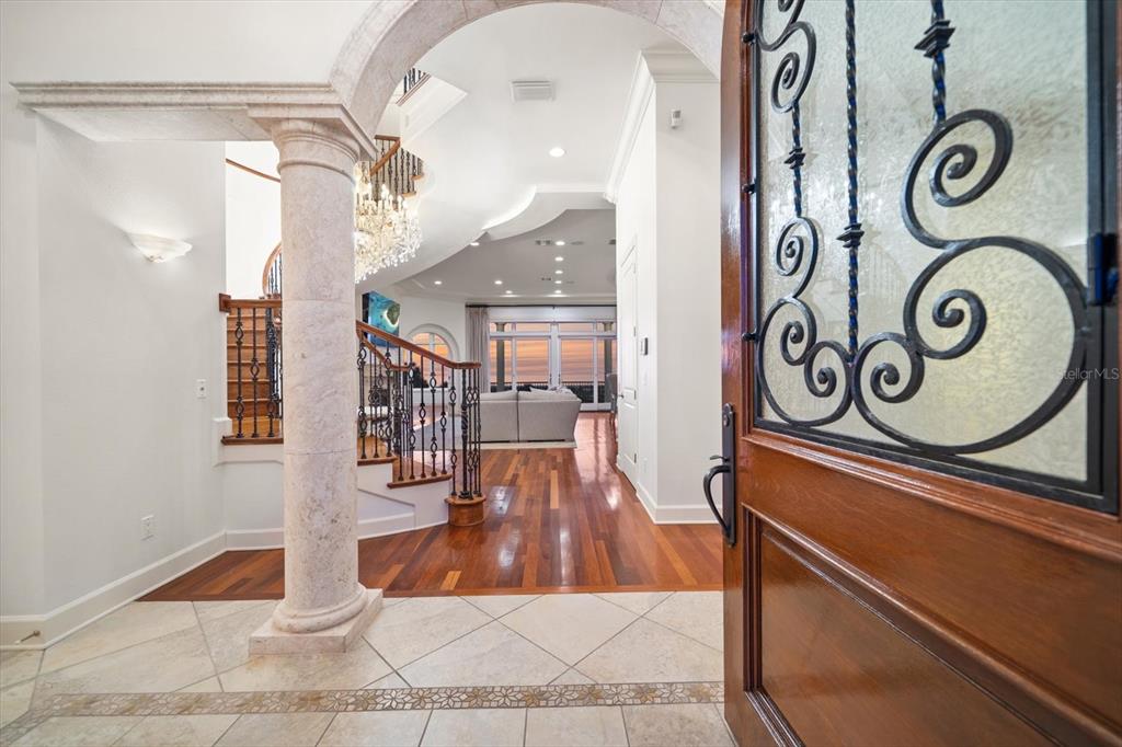 An entryway with a stone column, hardwood floors, and a staircase leads to a living area — 1040 ELDORADO AVENUE, CLEARWATER BEACH, FL