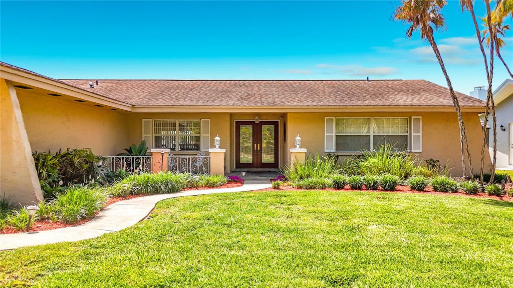 A single-story house with a tan exterior, a brown shingled roof, and a front lawn — 6490 BURNING TREE DRIVE, SEMINOLE, FL