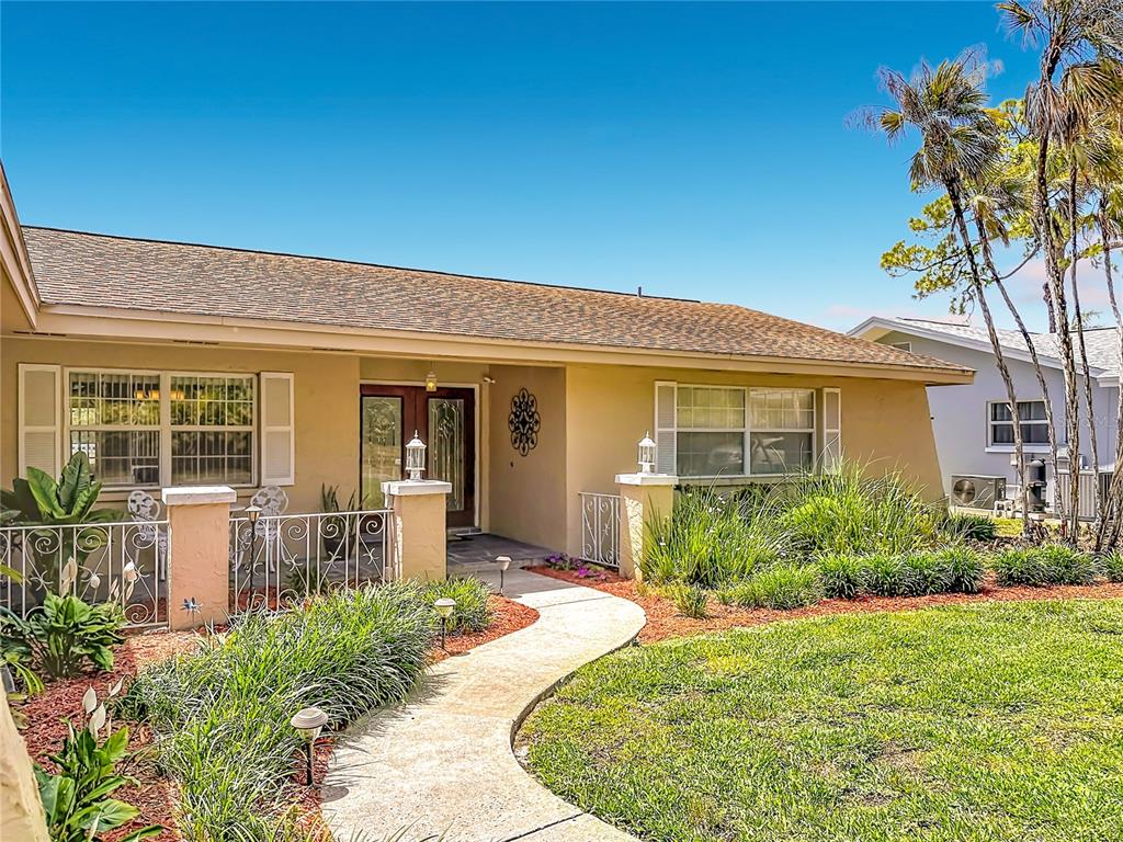 A single-story house with a tan exterior, a curved walkway, and a landscaped front yard — 6490 BURNING TREE DRIVE, SEMINOLE, FL