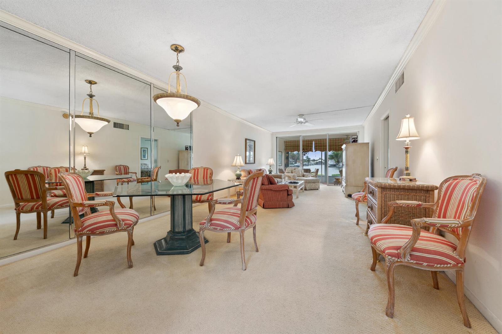 A dining area with a glass table and striped chairs sits before a mirrored wall — 3100 S Ocean Boulevard # 116, Highland Beach FL 33487, HIGHLAND BEACH, FL
