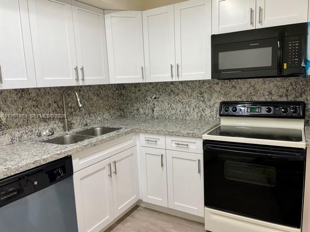 A kitchen features white cabinets, granite countertops, and black appliances — 1754 NW 55th Ave # 102, Lauderhill FL 33313, LAUDERHILL, FL