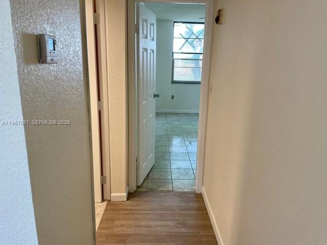 A hallway with wood-look flooring leads to an open doorway revealing a tiled room — 1754 NW 55th Ave # 102, Lauderhill FL 33313, LAUDERHILL, FL