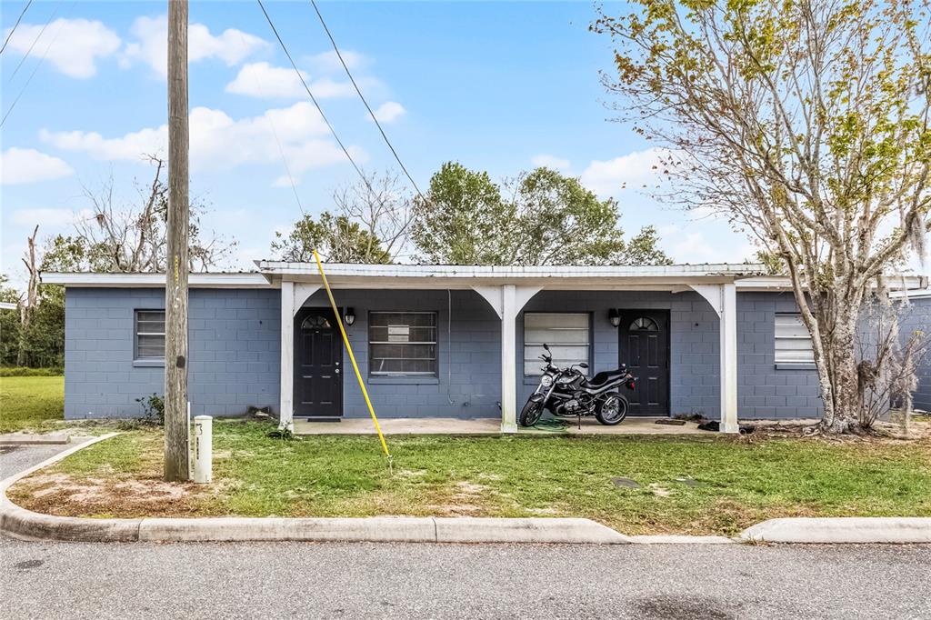 A single-story gray concrete block building with a covered porch and two front doors — 1086 HIBISCUS COURT UNIT 22, TAVARES, FL