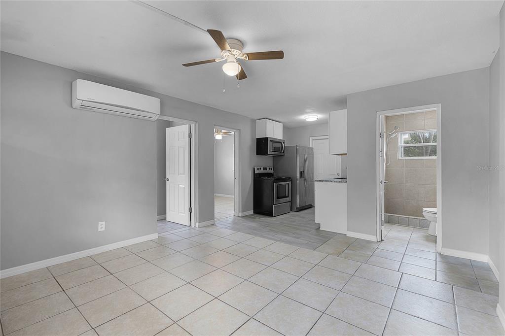 A living room with tile flooring, a ceiling fan, and an open kitchen area — 1086 HIBISCUS COURT UNIT 22, TAVARES, FL