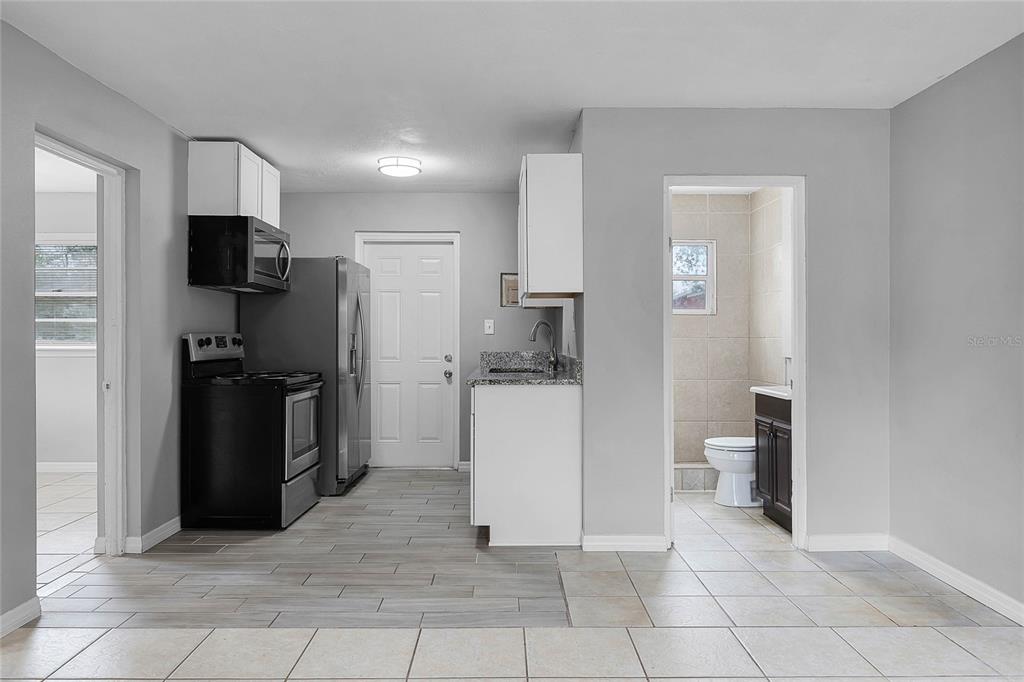 A kitchen with gray walls, white cabinets, stainless steel appliances, and a tiled floor — 1086 HIBISCUS COURT UNIT 22, TAVARES, FL