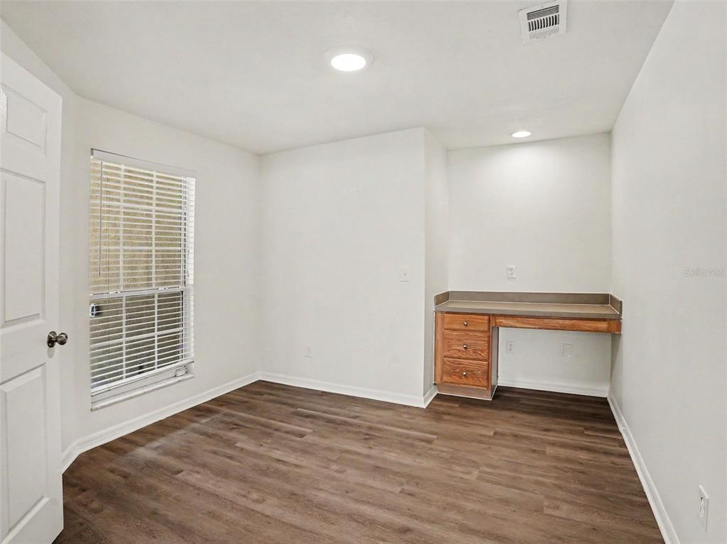 A room with wood-look flooring, a window with blinds, and a built-in wooden desk — 447 LANCER OAK DRIVE, APOPKA, FL