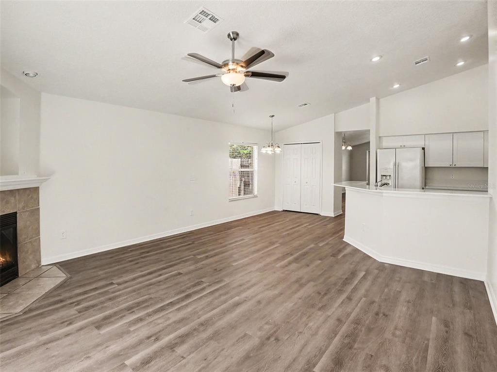An open-concept living room and kitchen area featuring wood-look flooring and a fireplace — 447 LANCER OAK DRIVE, APOPKA, FL