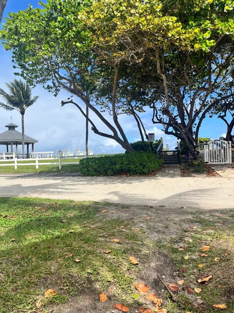 A paved path leads toward a gazebo, white fencing, and a gated entrance near trees — 5550 N Ocean Boulevard # 107, Ocean Ridge FL 33435, OCEAN RIDGE, FL