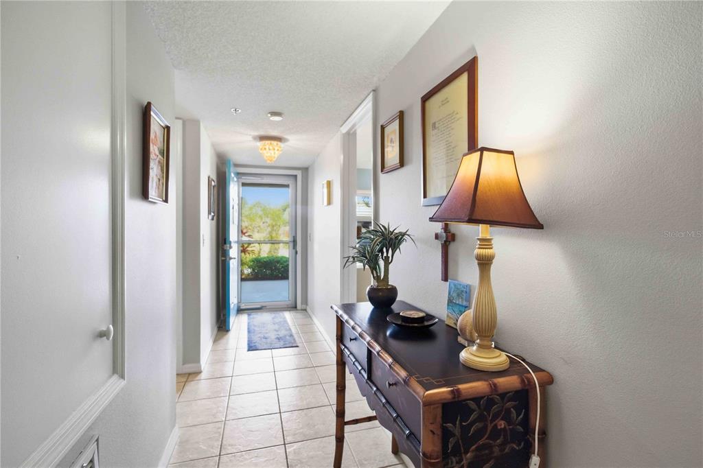 A tiled entryway leads to an open front door with a console table and lamp — 7301 29TH AVENUE DR W UNIT 105, BRADENTON, FL