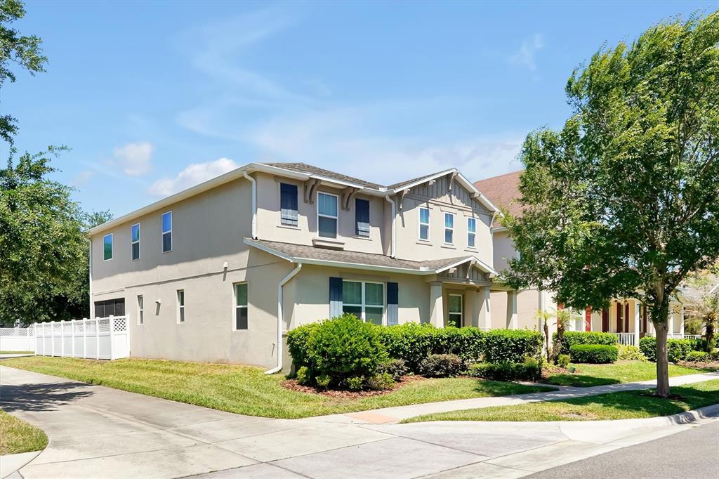 A two-story suburban house with a beige stucco exterior and a white vinyl fence — 7922 WINTER WREN STREET, WINTER GARDEN, FL
