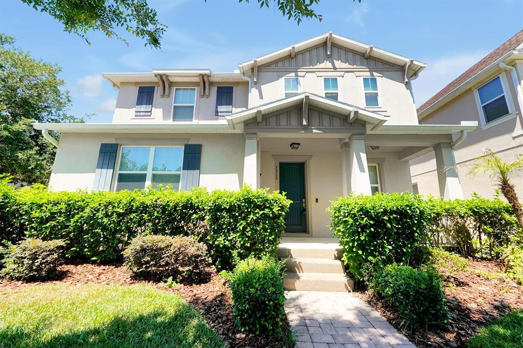A two-story suburban house with a front porch, hedges, and a paved walkway — 7922 WINTER WREN STREET, WINTER GARDEN, FL