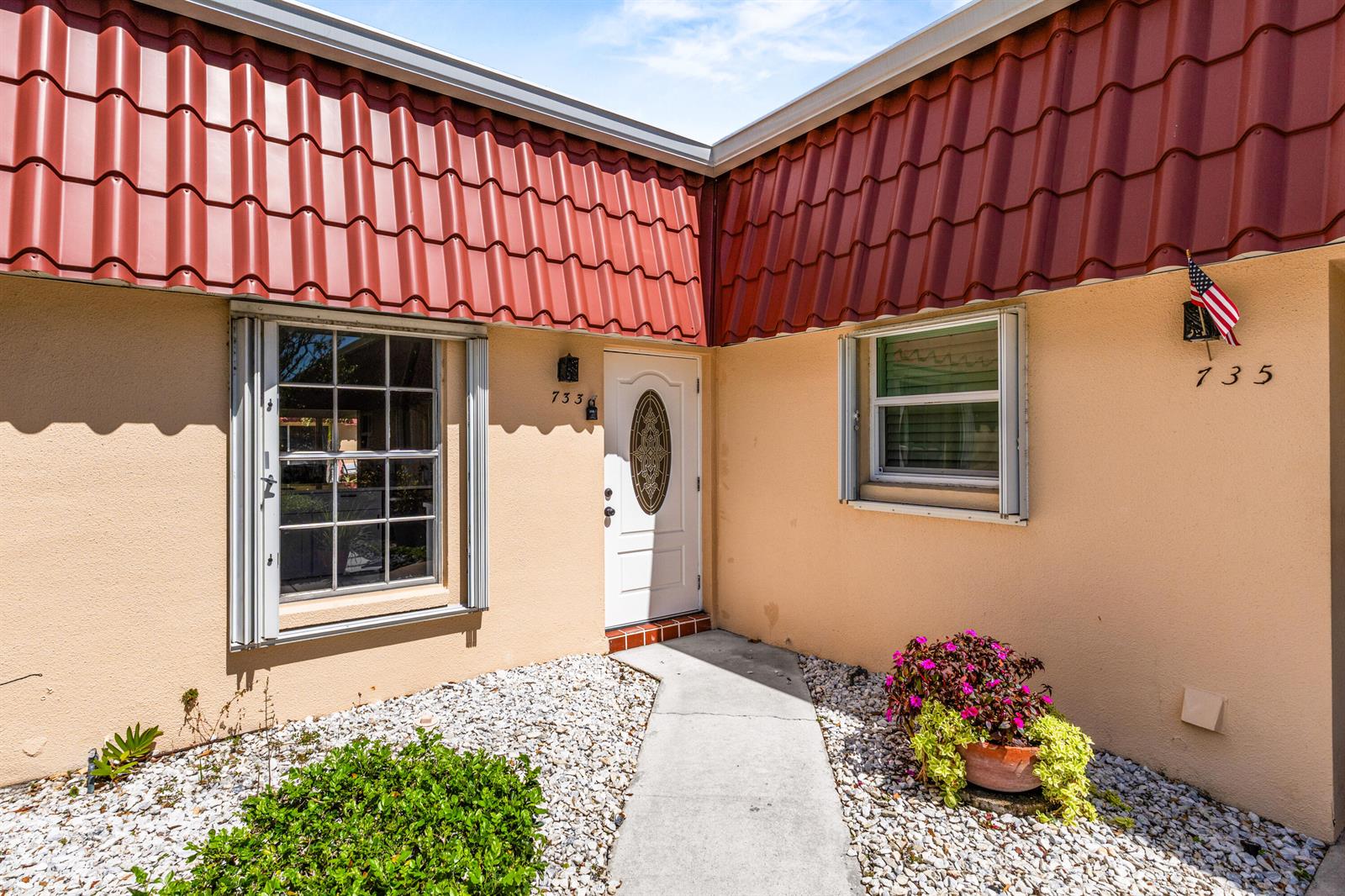 The exterior of a house features a red tile roof, beige stucco walls, and a walkway — 733 Nantucket Circle, Lake Worth FL 33467, LAKE WORTH, FL