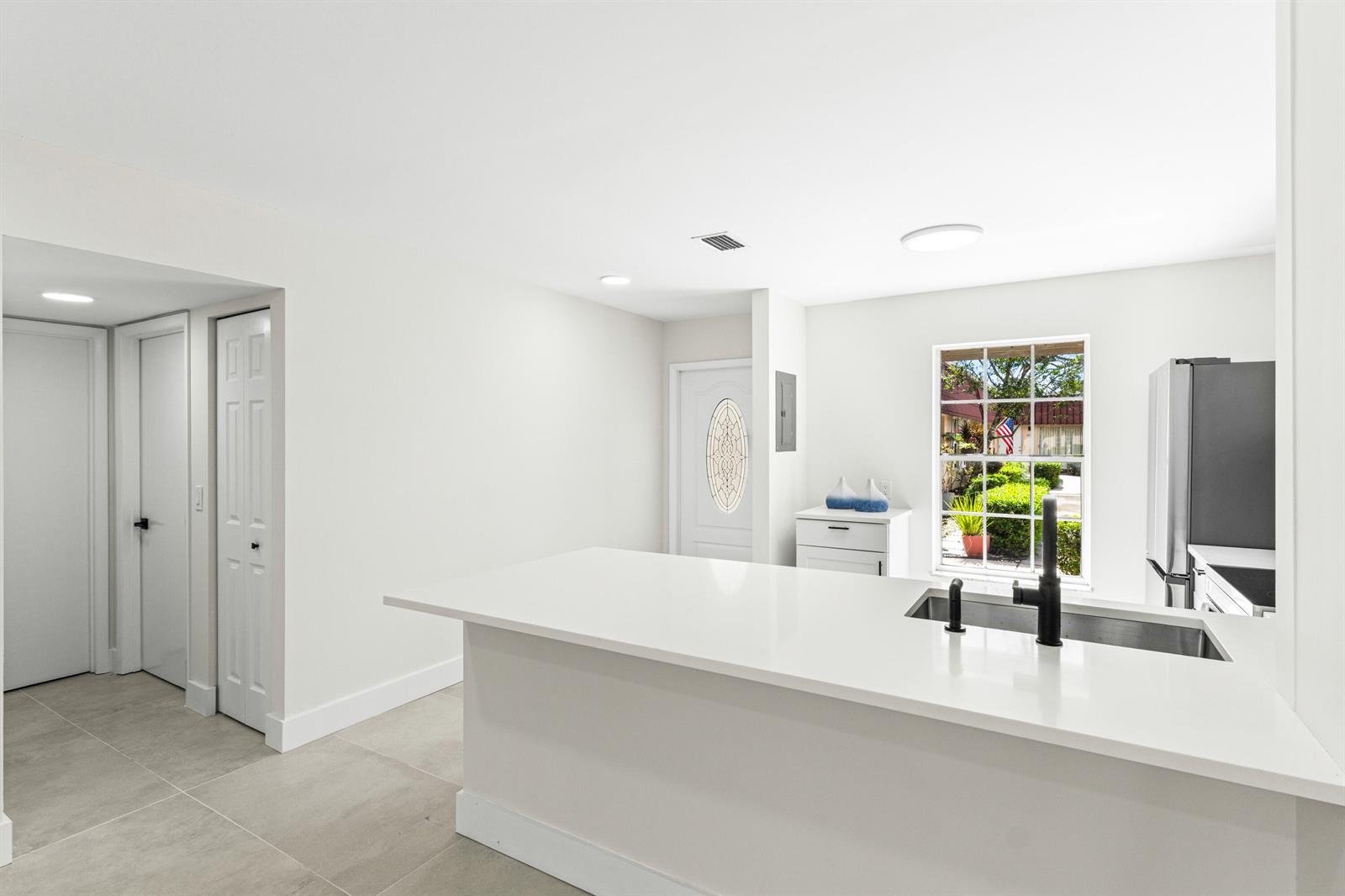 A kitchen features a white quartz peninsula, a stainless steel sink, and light tile flooring — 733 Nantucket Circle, Lake Worth FL 33467, LAKE WORTH, FL