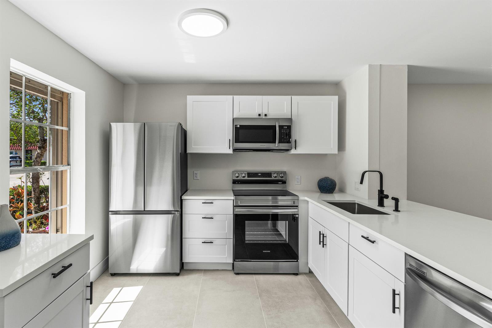 A modern kitchen features white cabinets, stainless steel appliances, and a window with outdoor views — 733 Nantucket Circle, Lake Worth FL 33467, LAKE WORTH, FL
