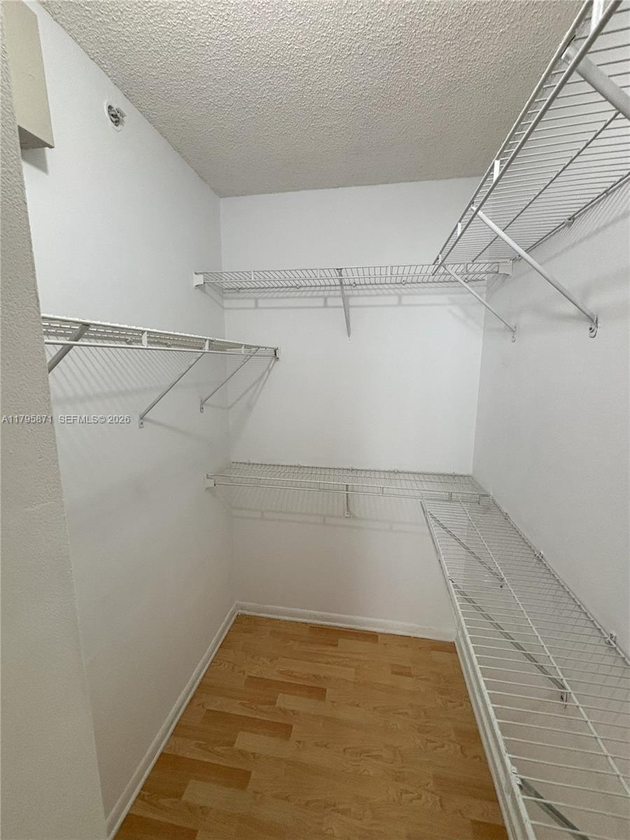 A walk-in closet features white wire shelving, white walls, and light wood-look flooring — 126 SW 17th Rd # 505, Miami FL 33129, MIAMI, FL
