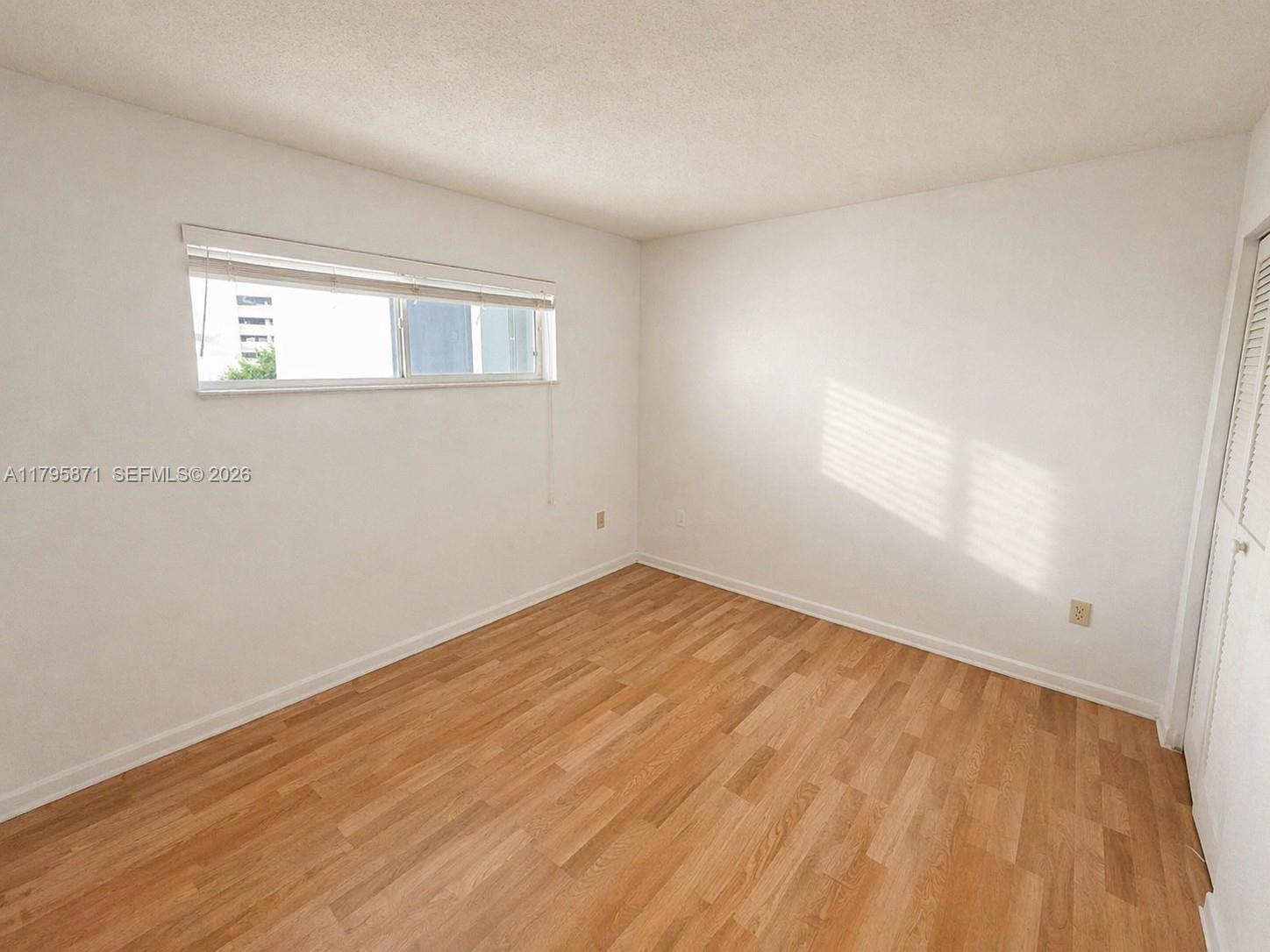 An empty bedroom features white walls, light wood-look flooring, and a horizontal window — 126 SW 17th Rd # 505, Miami FL 33129, MIAMI, FL