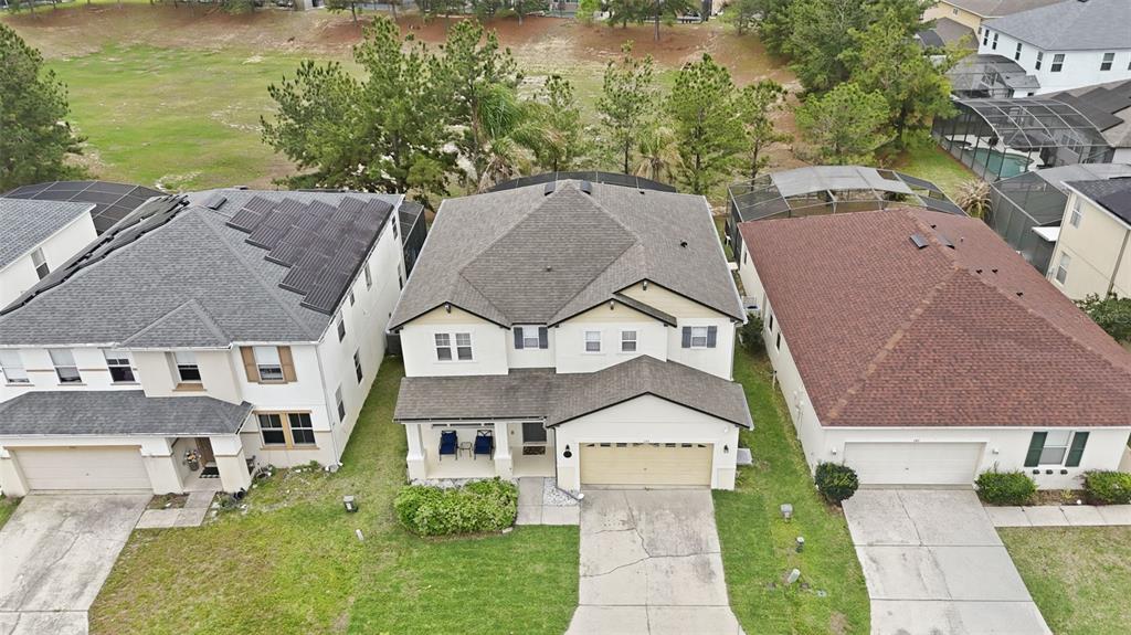 An aerial view shows three suburban houses with driveways and lawns, including one with solar panels — 133 BAY LEAF LANE, DAVENPORT, FL