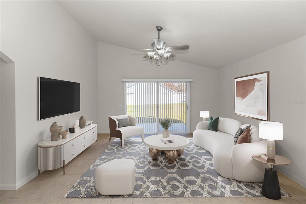 This is a digitally staged living room featuring a curved sofa, area rug, and television — 2989 WHITE CEDAR CIRCLE, KISSIMMEE, FL