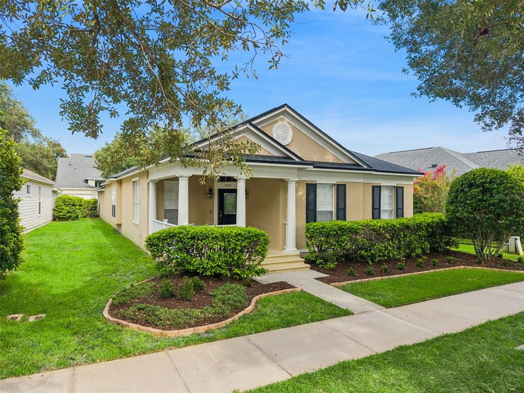 A tan single-story house with a front porch, white columns, and manicured landscaping — 9615 SWEETLEAF STREET, ORLANDO, FL