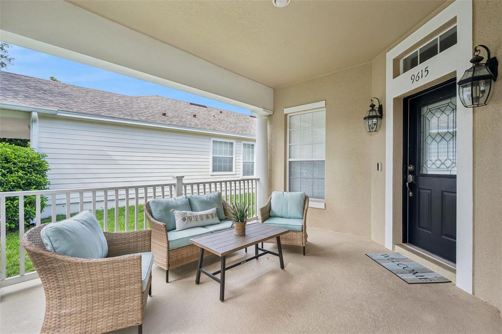 A covered front porch features wicker furniture, a small table, and a black front door — 9615 SWEETLEAF STREET, ORLANDO, FL
