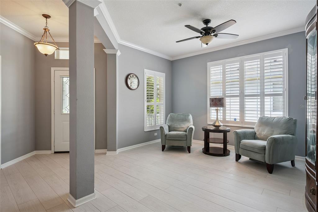 A living room with light gray walls, two armchairs, a side table, and white shutters — 9615 SWEETLEAF STREET, ORLANDO, FL