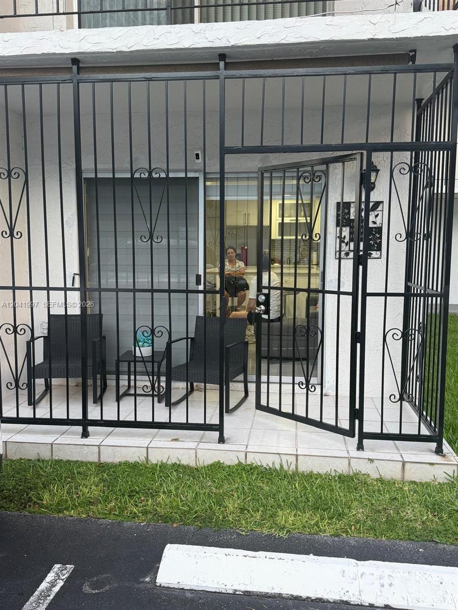 A ground-floor patio features black metal security bars, two chairs, and a small table — 9520 SW 8th St # 121, Miami FL 33174, MIAMI, FL