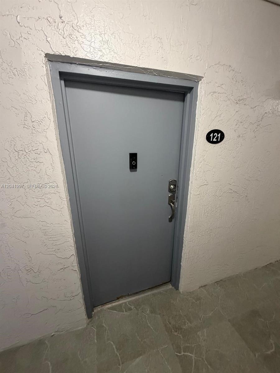 A gray apartment door with a doorbell camera and number 121 is set in a wall — 9520 SW 8th St # 121, Miami FL 33174, MIAMI, FL