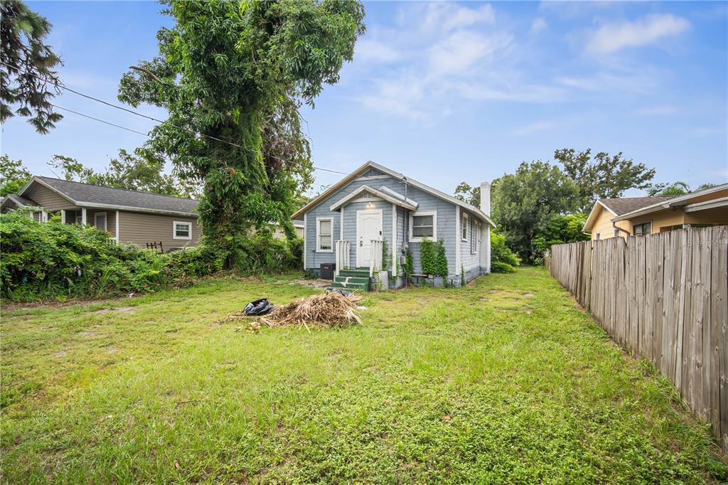 A blue house with a white door sits in a grassy yard with a wooden fence — 3535 14TH AVENUE S, ST PETERSBURG, FL