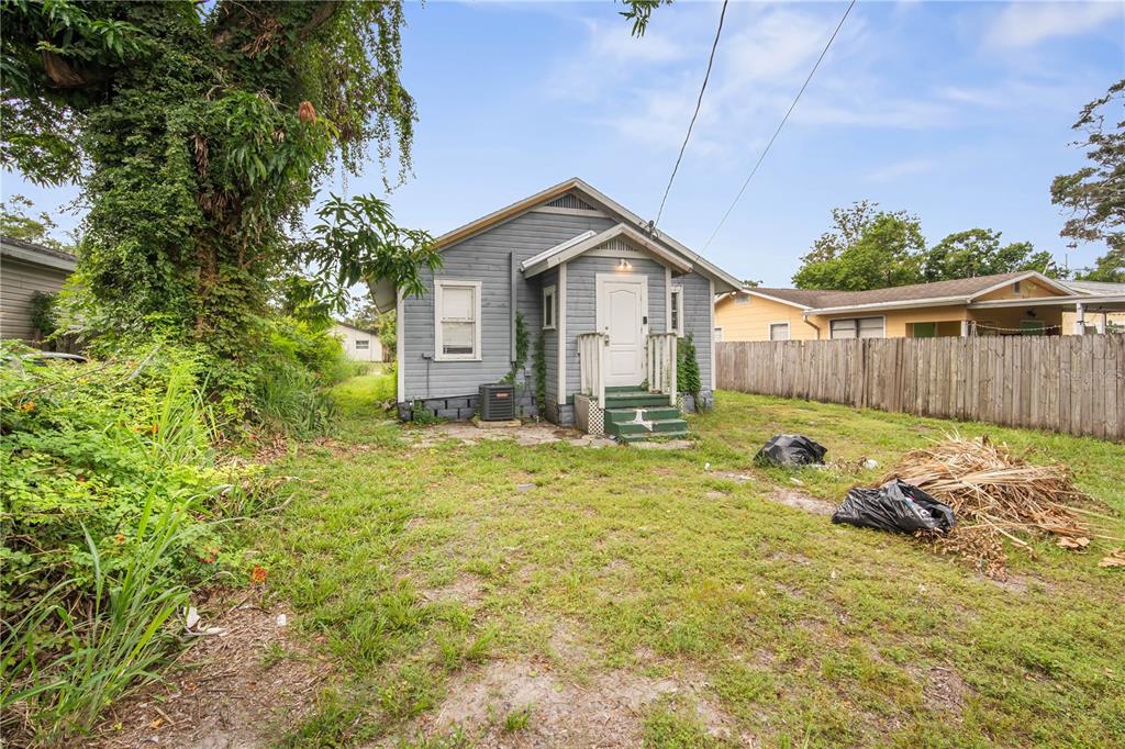A small, gray-sided house with a front porch stands in a grassy, partially overgrown yard — 3535 14TH AVENUE S, ST PETERSBURG, FL