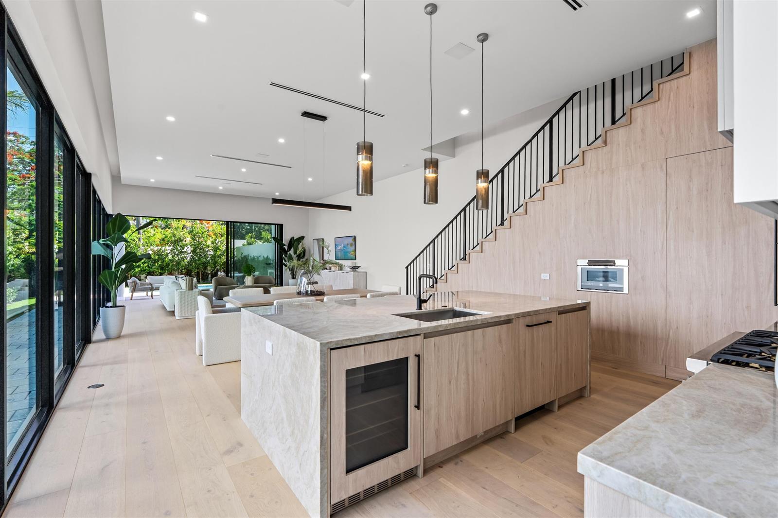 A modern kitchen with a stone island and wood cabinetry opens to a living area — 723 Lake Avenue N, Delray Beach FL 33483, DELRAY BEACH, FL