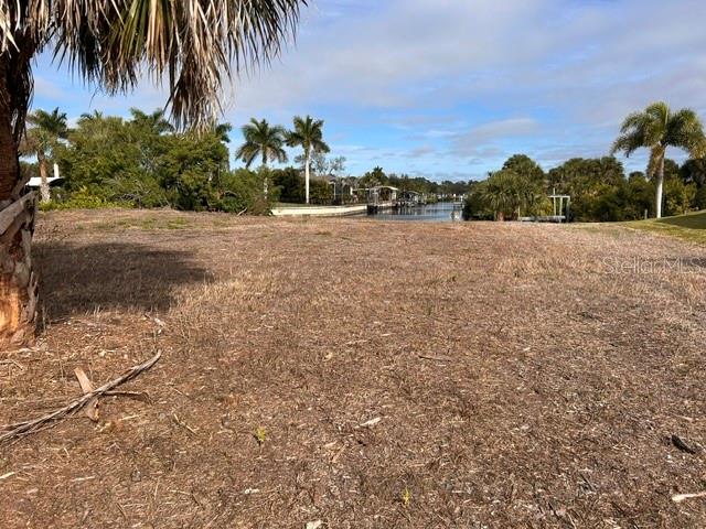 A vacant, grassy waterfront lot features palm trees and a view of a canal — 17542 OHARA DRIVE, PORT CHARLOTTE, FL