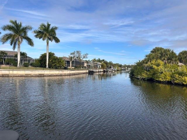 A view of a canal lined with palm trees, houses, and lush vegetation under a sky — 17542 OHARA DRIVE, PORT CHARLOTTE, FL