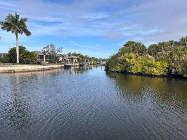A canal view showing houses on the left and dense vegetation on the right — 17542 OHARA DRIVE, PORT CHARLOTTE, FL