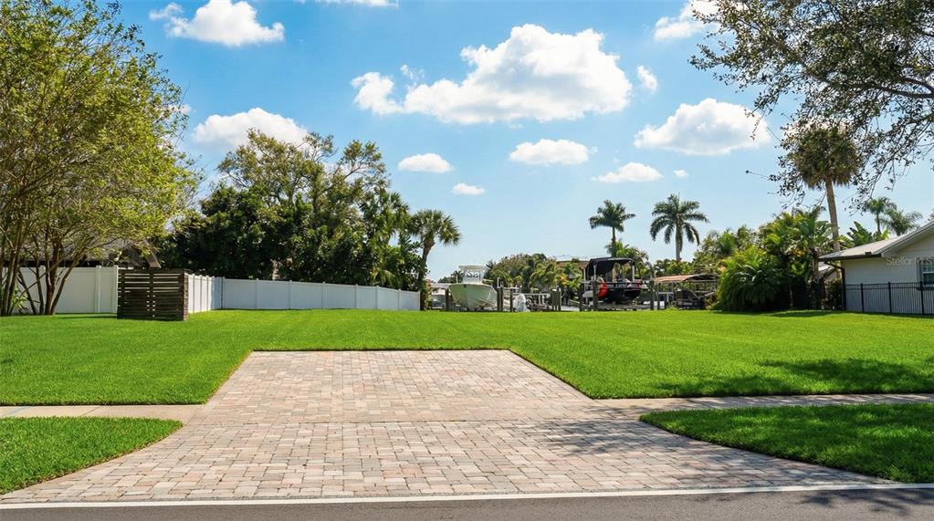 A paved driveway leads to a large, grassy vacant lot with a white fence — 3904 DANA SHORES DRIVE, TAMPA, FL