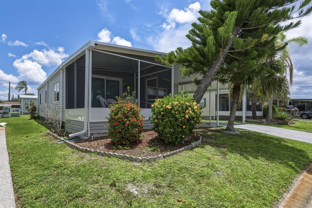 A manufactured home features a screened-in porch, a concrete driveway, and landscaped front yard bushes — 2100 KINGS HIGHWAY UNIT 522, PORT CHARLOTTE, FL