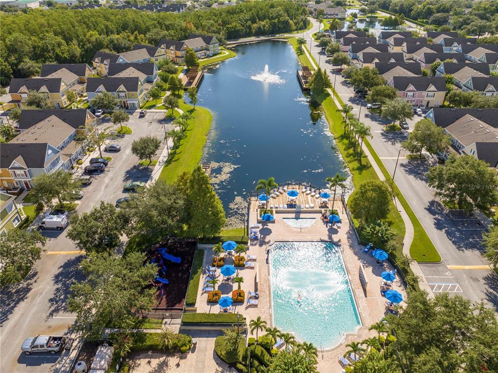 An aerial view shows a residential community with a central lake, swimming pool, and playground — 4011 VENETIAN BAY DRIVE UNIT 101, KISSIMMEE, FL