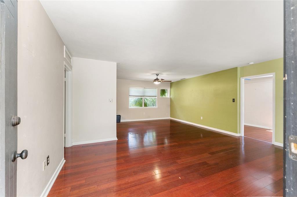 An interior view of a living area with hardwood floors and a green accent wall — 1038 NE 14TH AVENUE, GAINESVILLE, FL