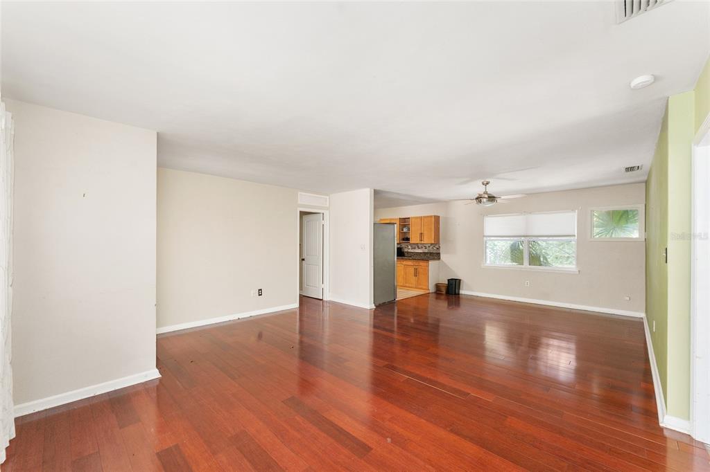 An open-concept living area features hardwood floors, a ceiling fan, and an adjacent kitchen — 1038 NE 14TH AVENUE, GAINESVILLE, FL