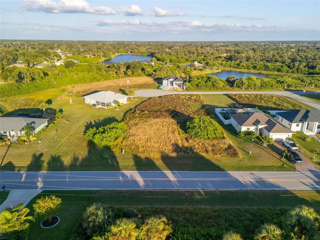 An aerial view shows a vacant residential lot situated between two houses near a lake — 278 INDIAN CREEK DRIVE, ROTONDA WEST, FL